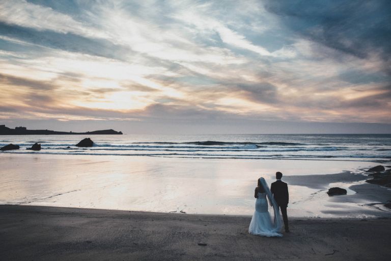 Bride and groom watch sunset on lusty glaze beach